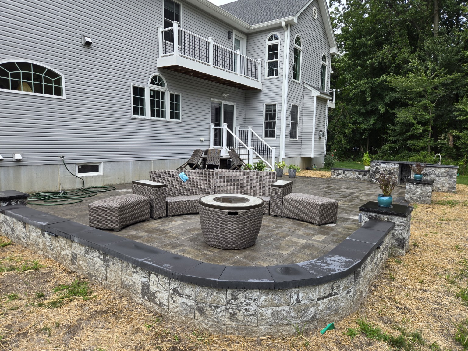 Custom patio with curved stone seating wall and outdoor furniture